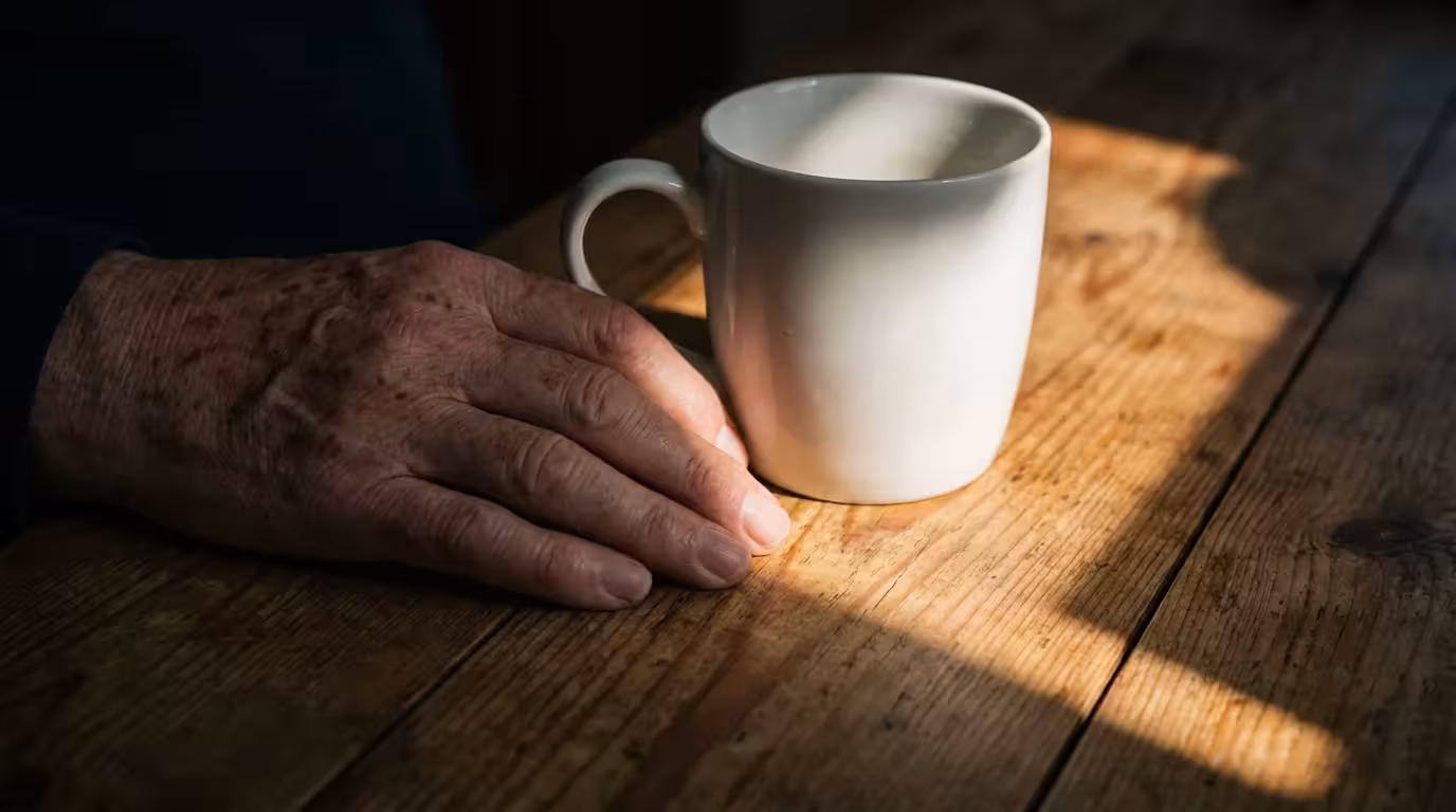 Close-up macro photo of sunlight and shadow falling across a hand and mug.
