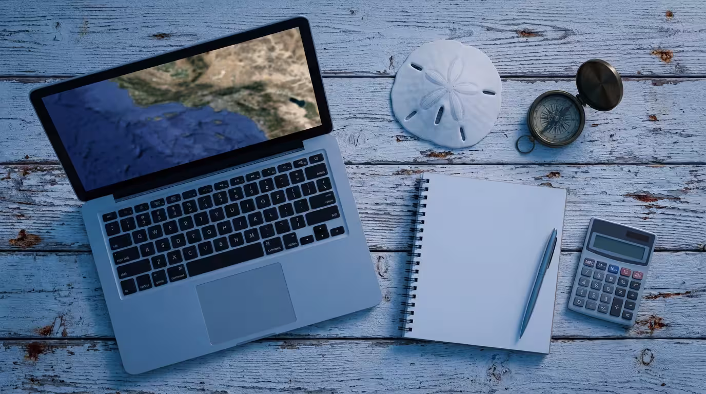 Flat lay of a laptop, notebook, and coastal objects for retirement relocation planning.